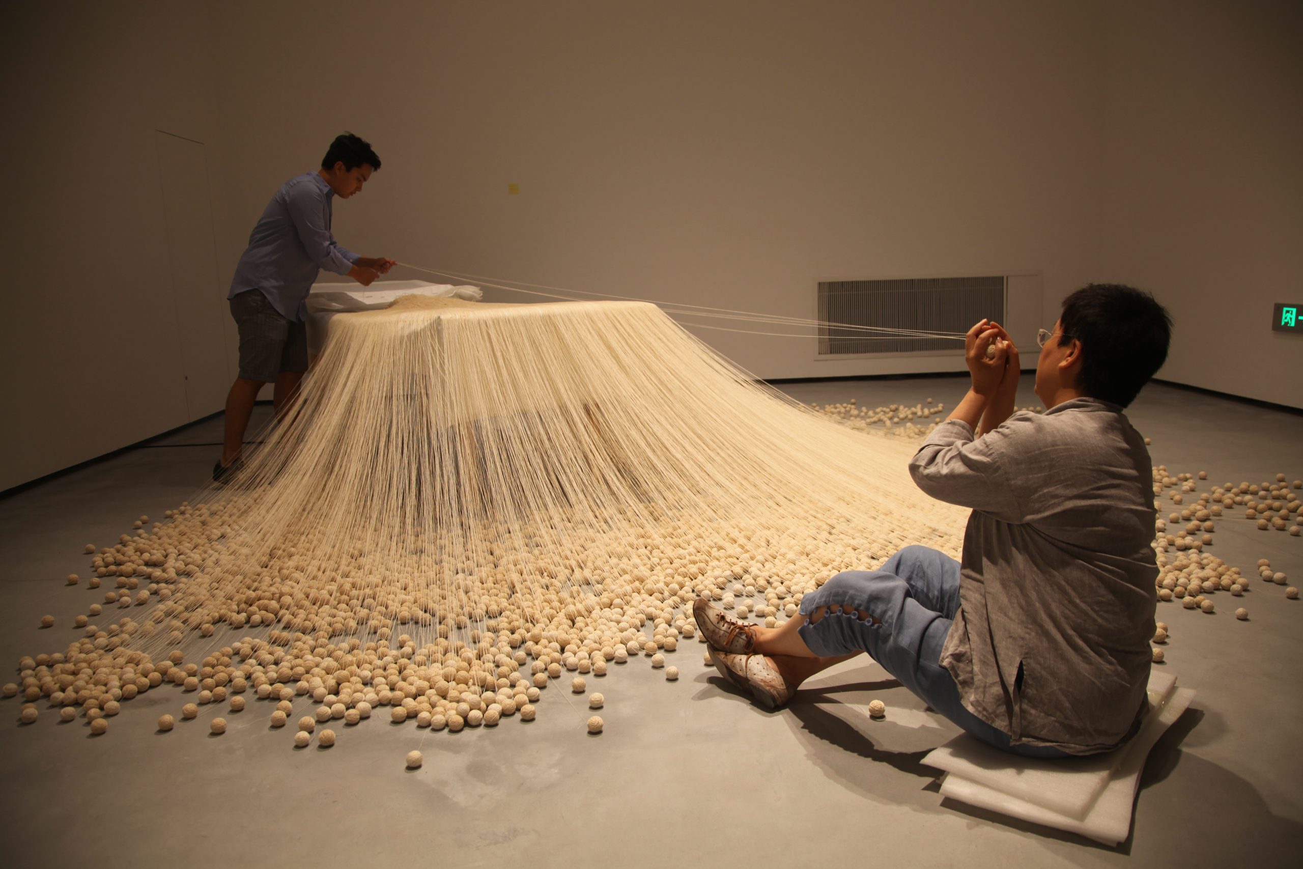 Lin Tianmiao and a studio assistant installing The Proliferation of Thread Winding (1995) for the exhibition The Civil Power, Minsheng Art Museum, 2015. Photo courtesy of the artist.