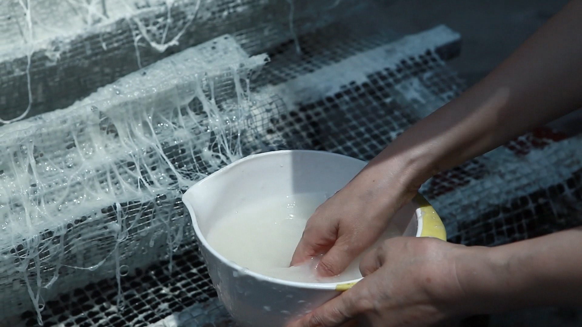 Shi Hui applying pulp to a mesh frame. Video still taken from Shi Hui directed by Chen Yi, produced by the China Academy of Art, Hangzhou.